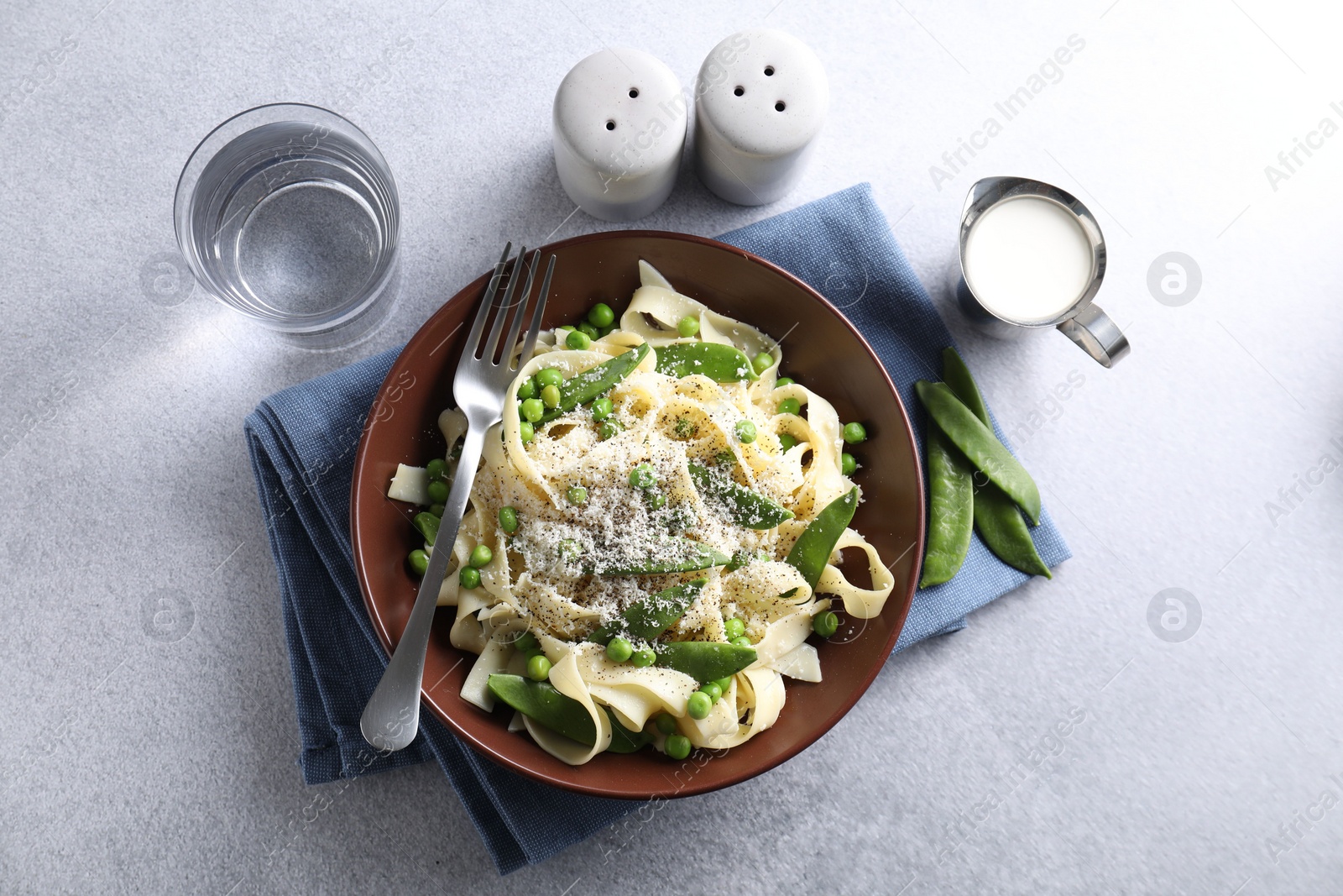 Photo of Delicious pasta with green peas and cheese served on grey table