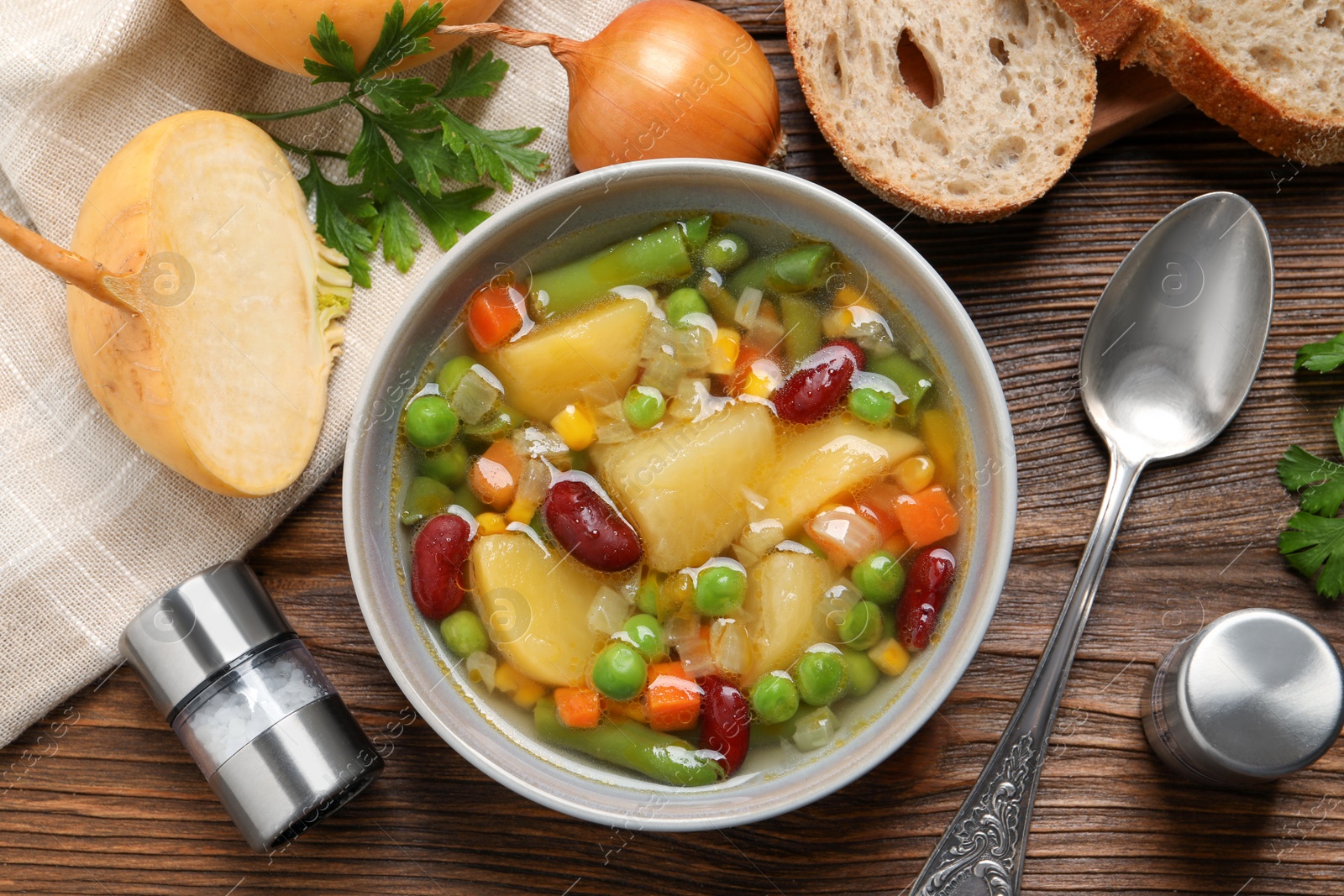 Photo of Bowl of delicious turnip soup served on wooden table, flat lay