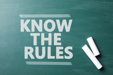Image of Phrase Know the rules and pieces of chalk on greenboard, top view