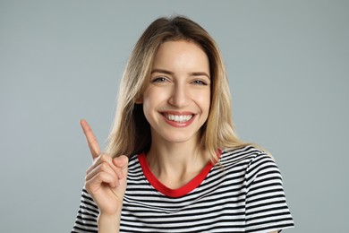 Photo of Woman showing number one with her hand on light grey background