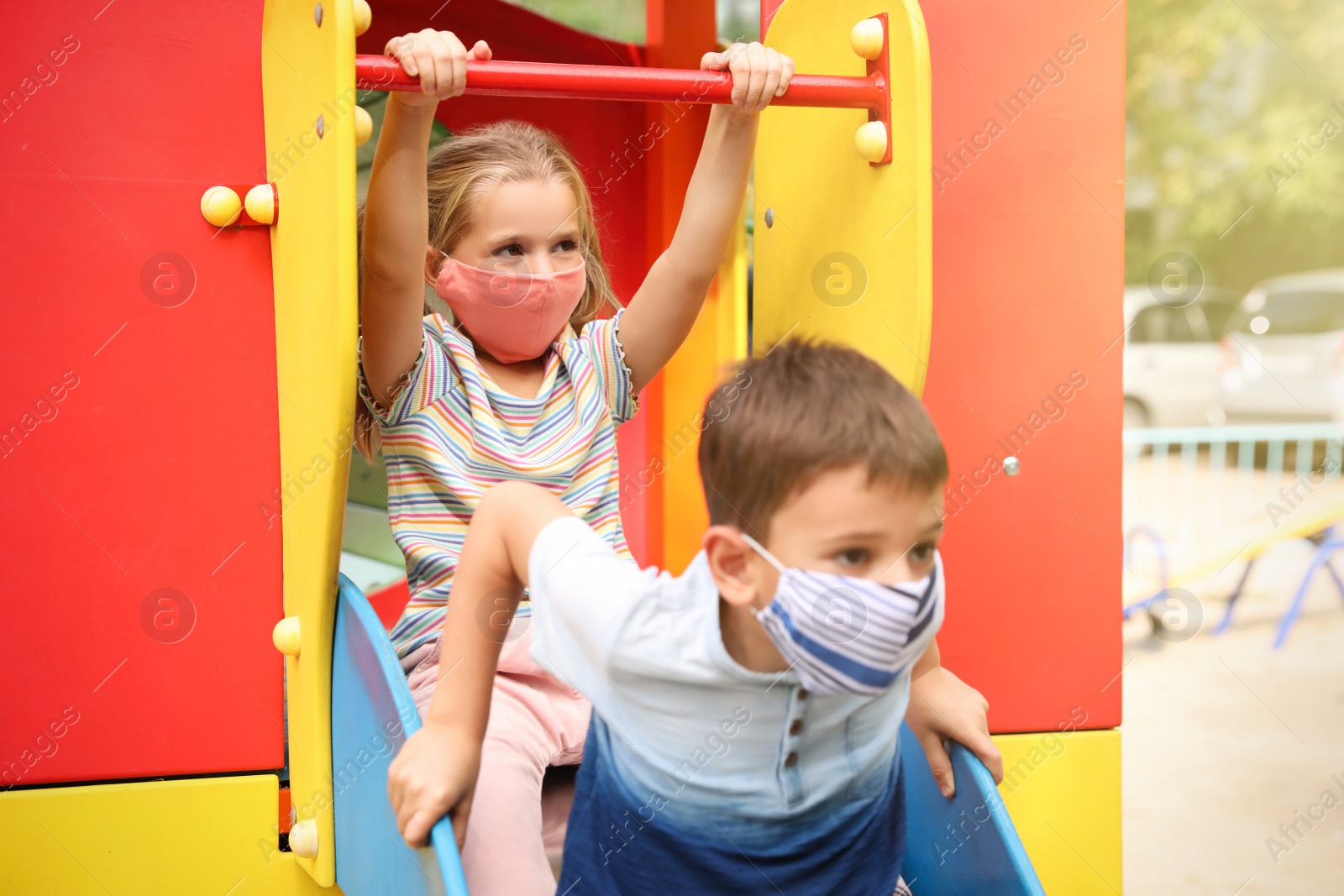 Photo of Little children with medical face masks on playground during covid-19 quarantine