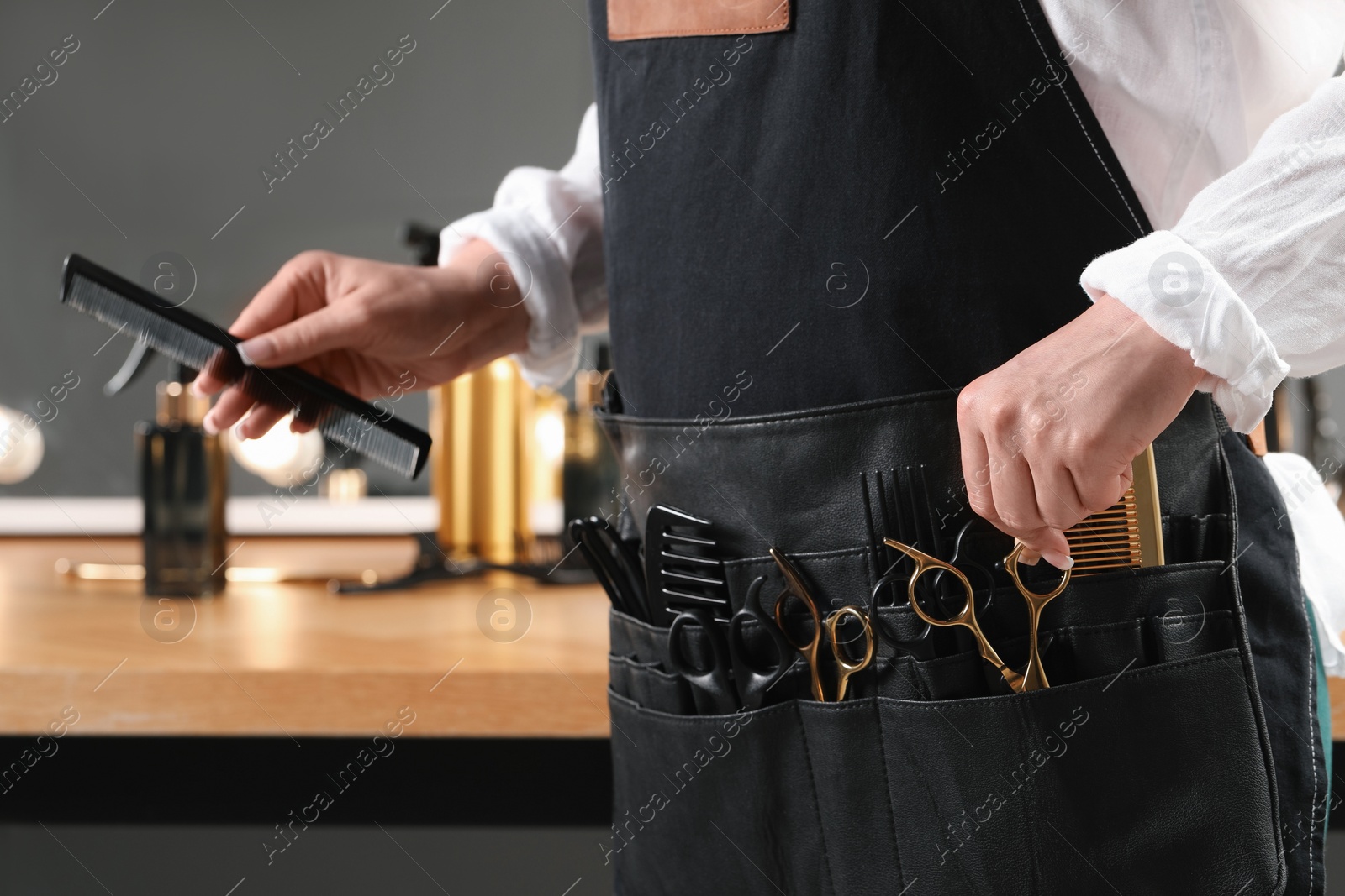 Photo of Hairstylist with professional tools in waist pouch in salon, closeup