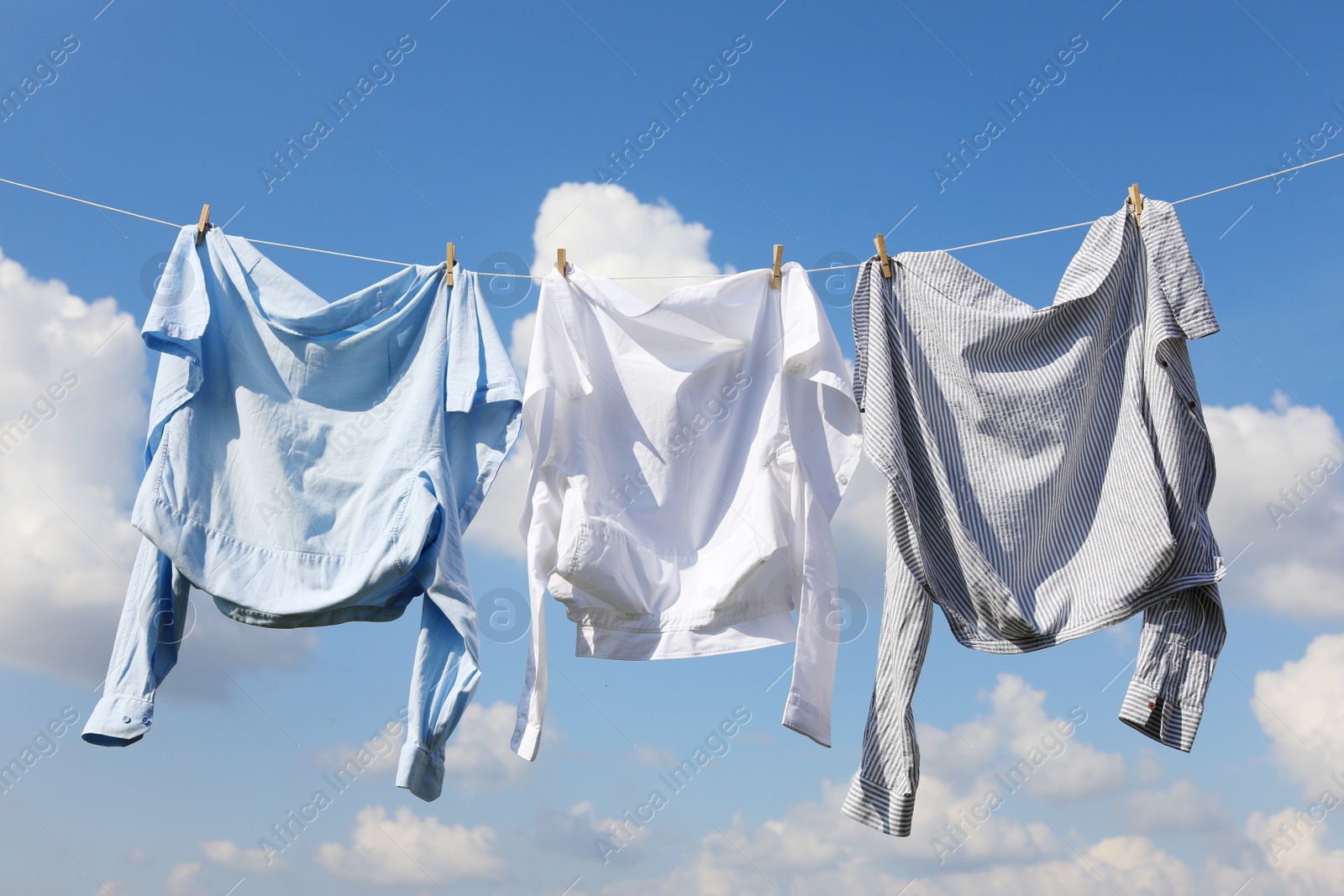 Photo of Clean clothes hanging on washing line against sky. Drying laundry