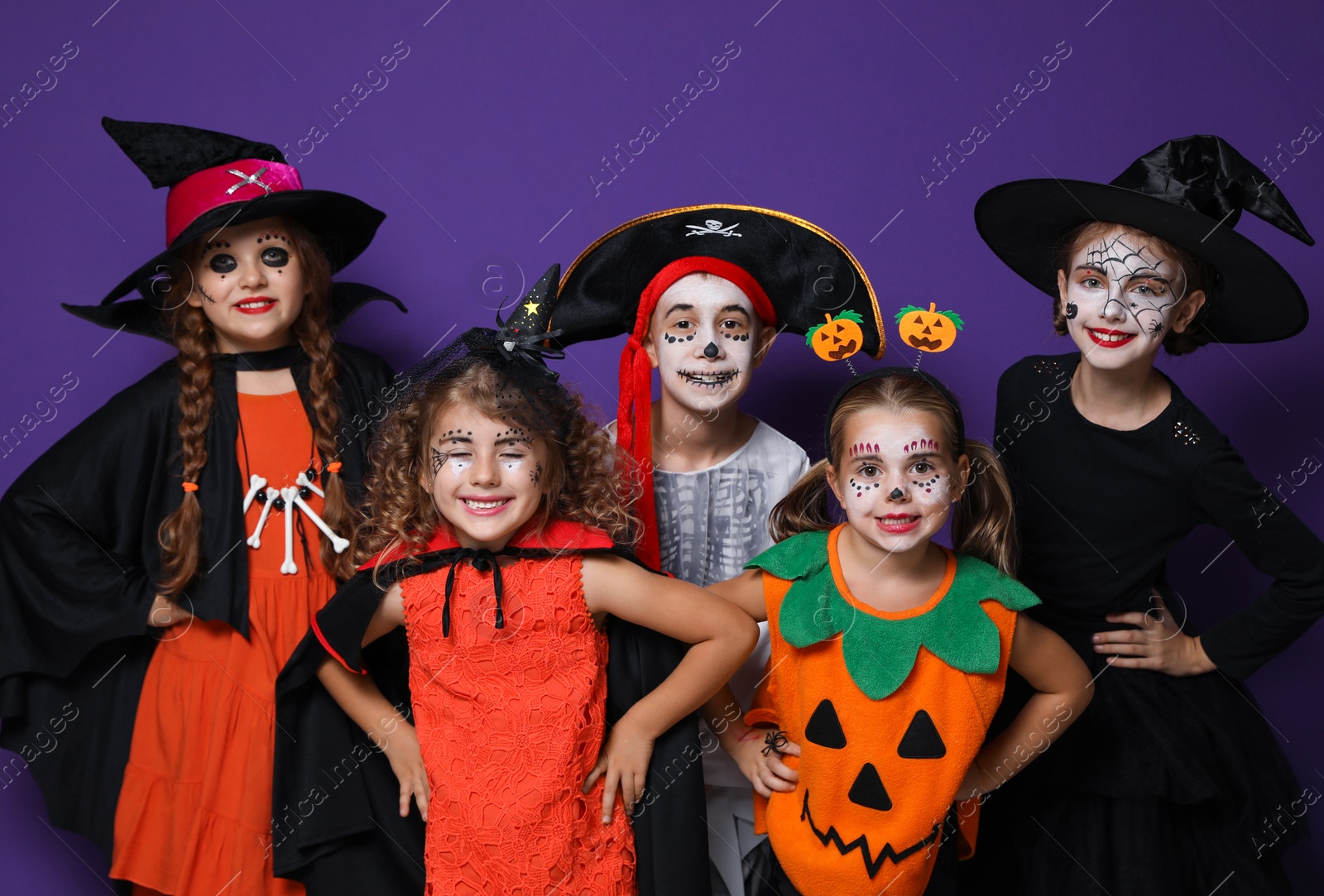 Photo of Cute little kids wearing Halloween costumes on purple background