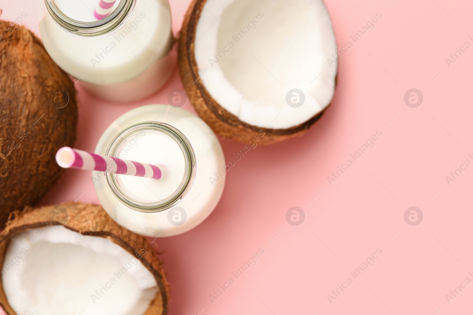 Photo of Delicious vegan milk and coconuts on pink background, flat lay. Space for text