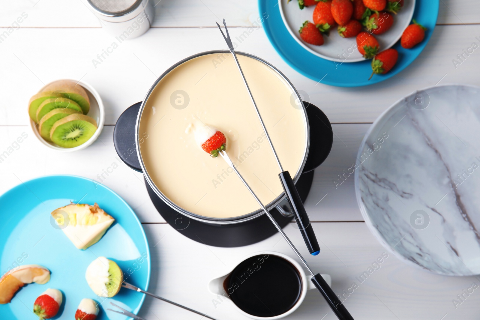 Photo of Flat lay composition with chocolate fondue in pot and fruits on wooden background