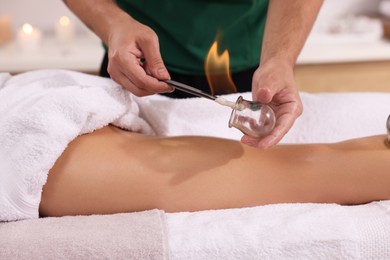 Photo of Therapist giving fire cupping treatment to patient indoors, closeup