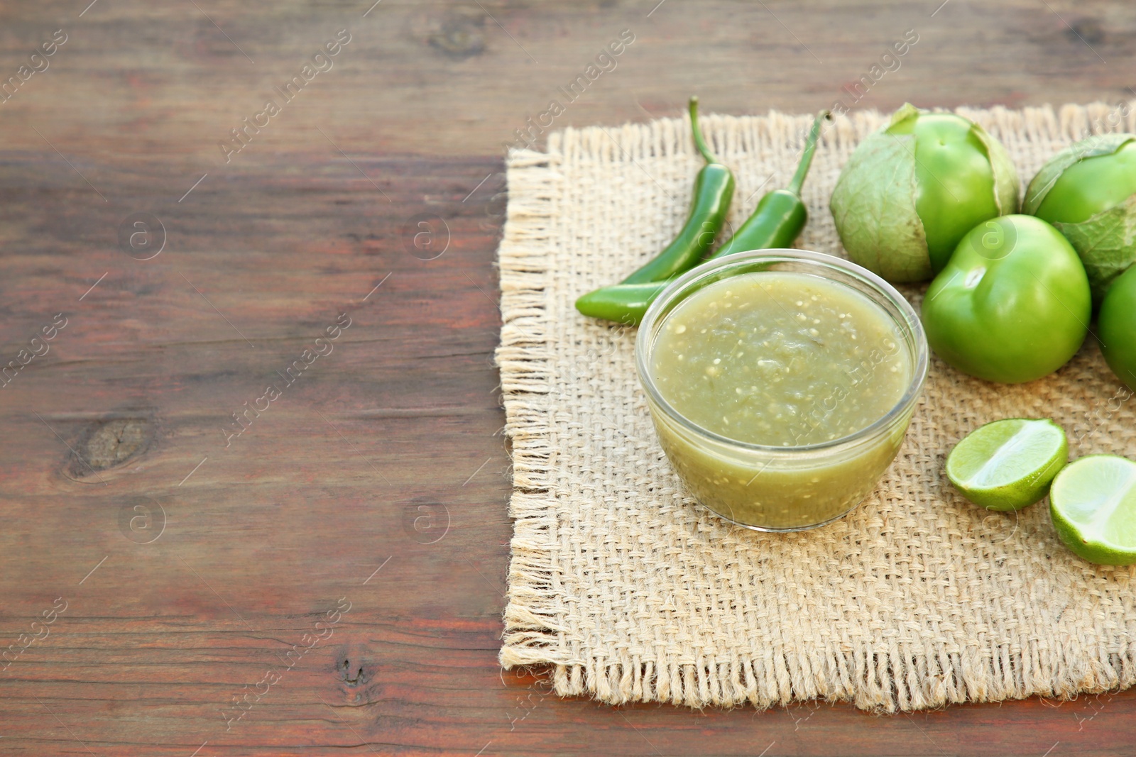 Photo of Tasty salsa sauce and ingredients on wooden table. Space for text