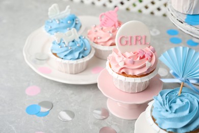 Delicious cupcakes with light blue and pink cream for baby shower on grey table