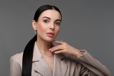 Photo of Beautiful young woman with elegant jewelry on dark grey background