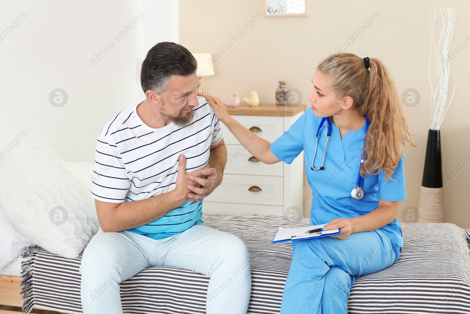 Photo of Female medical assistant consulting male patient during home visit