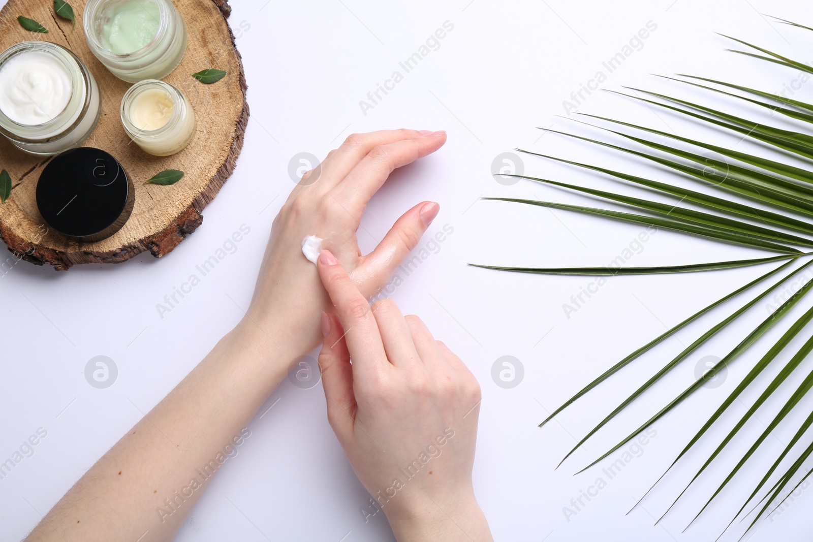 Photo of Woman applying hand cream on white background, top view