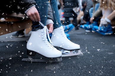 Young woman wearing white ice skates outdoors, closeup