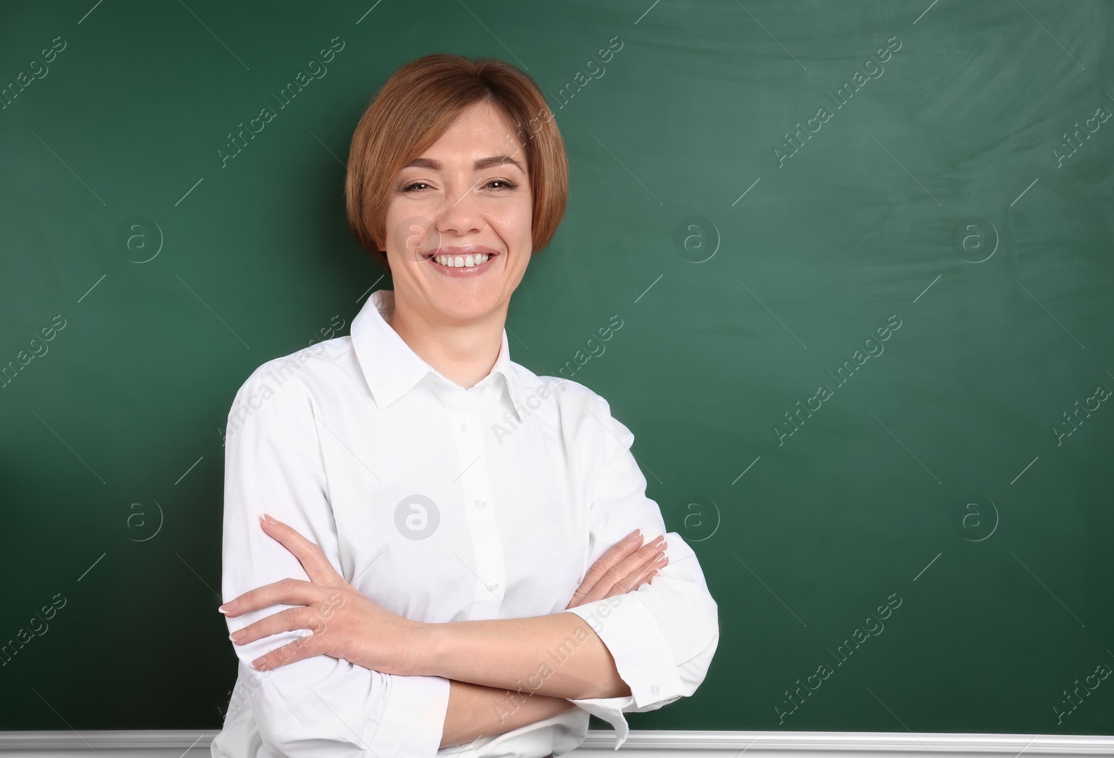 Photo of Portrait of female teacher near chalkboard