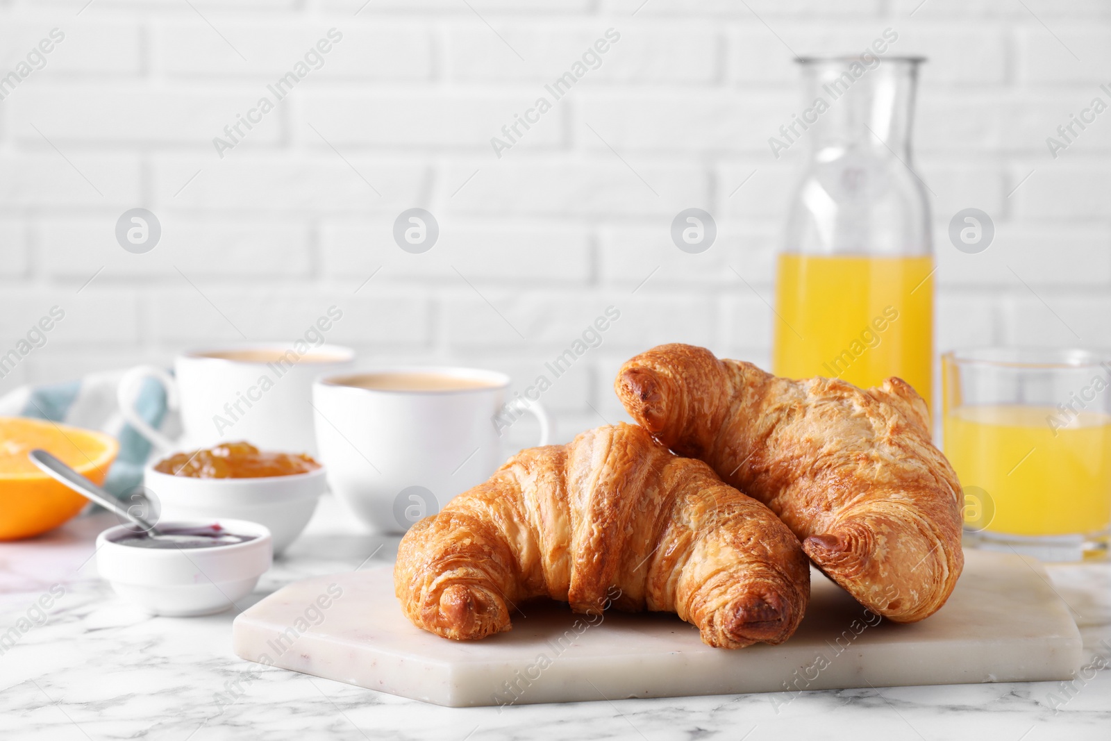 Photo of Tasty breakfast. Fresh croissants and jam on white marble table