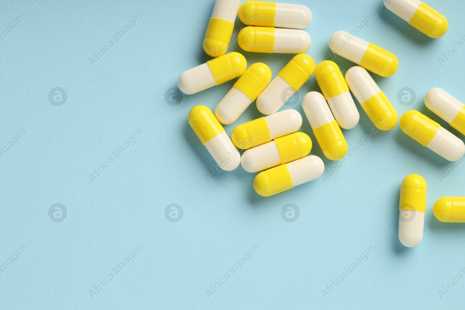 Photo of Many antibiotic pills on light blue background, top view. Space for text