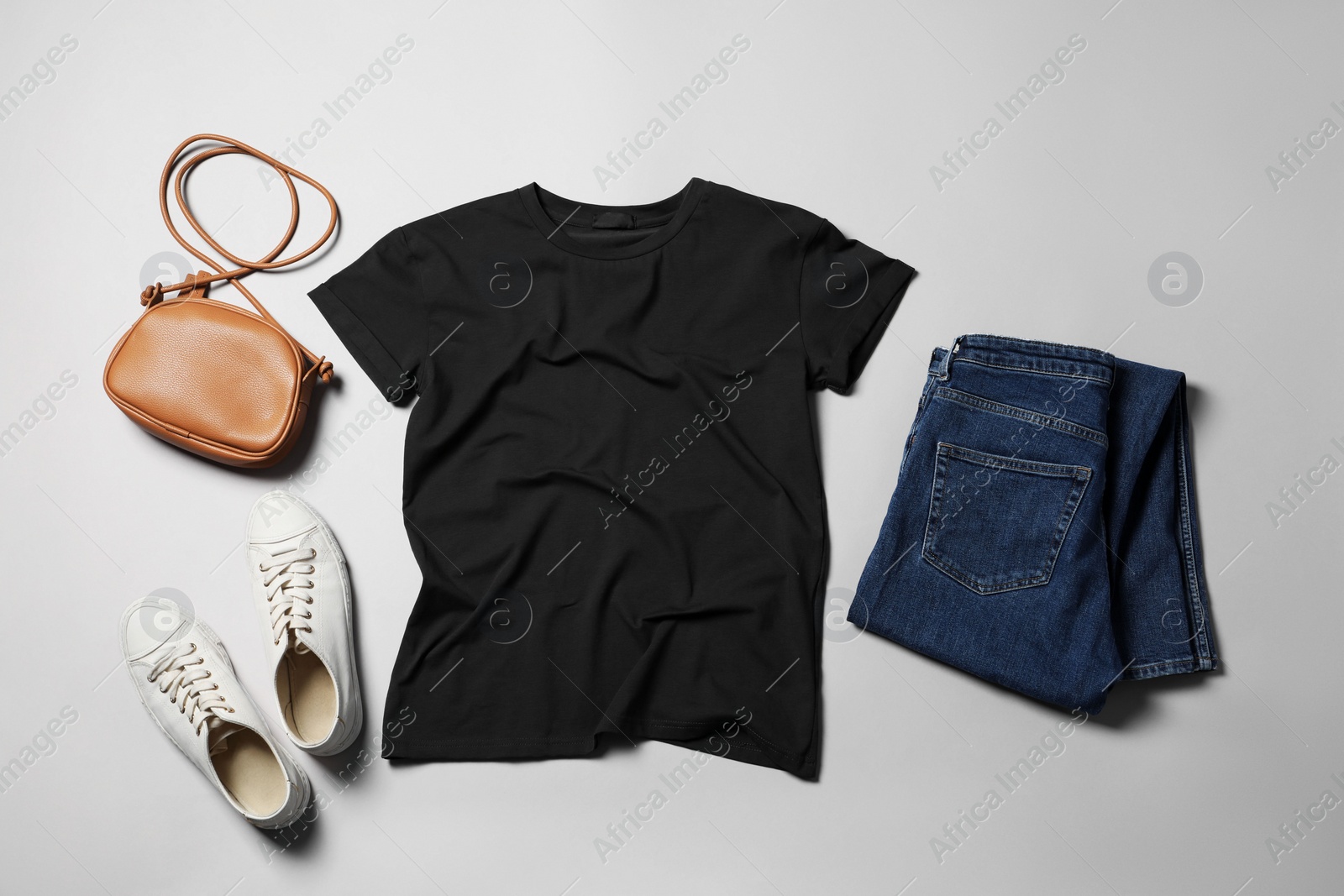 Photo of Stylish t-shirt, jeans and sneakers on light grey background, flat lay