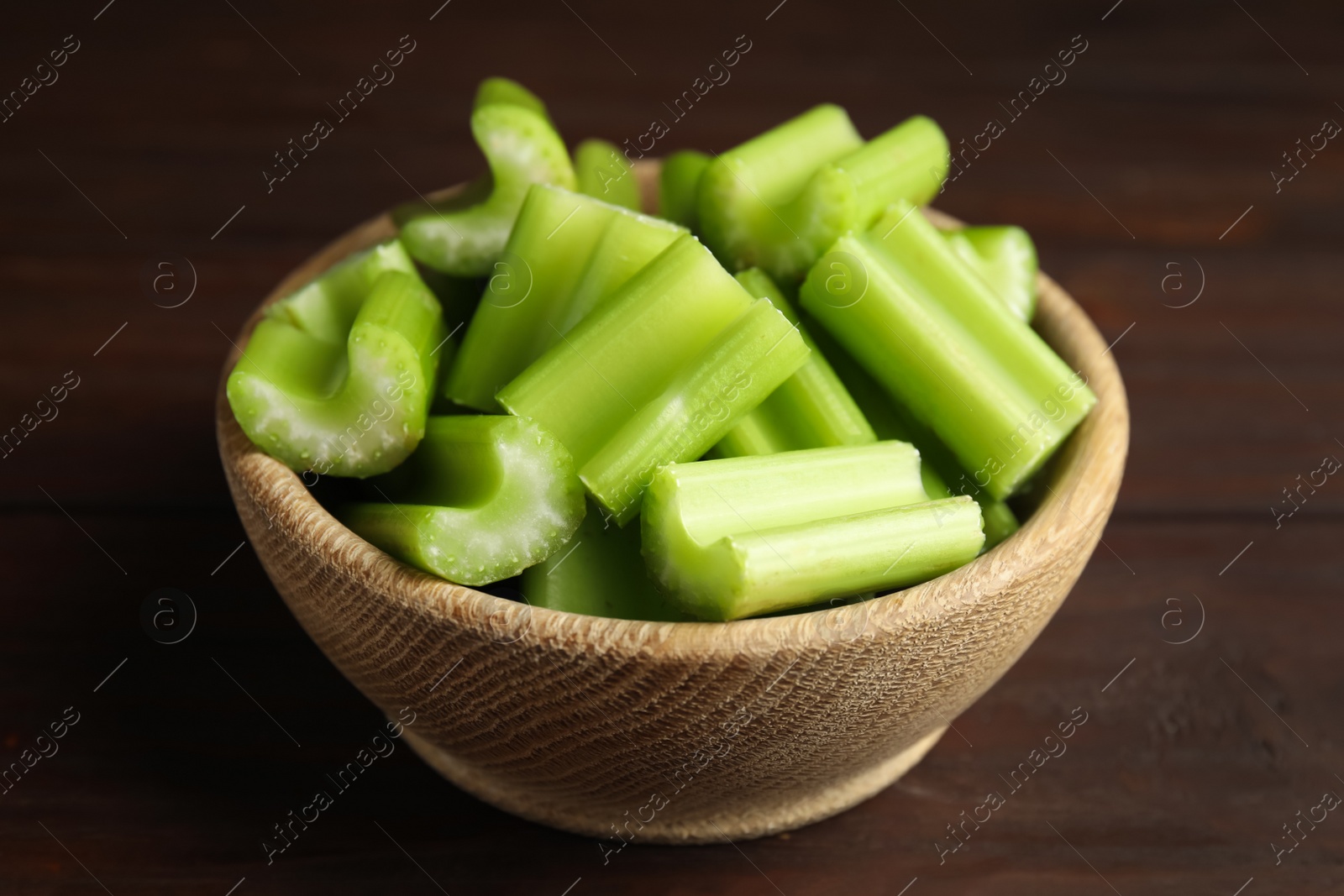 Photo of Cut celery in bowl on wooden table