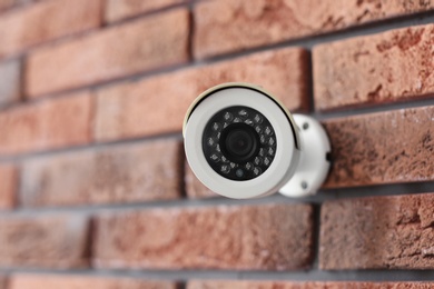 Photo of Modern security CCTV camera on brick wall