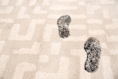Trail of muddy footprints on beige carpet