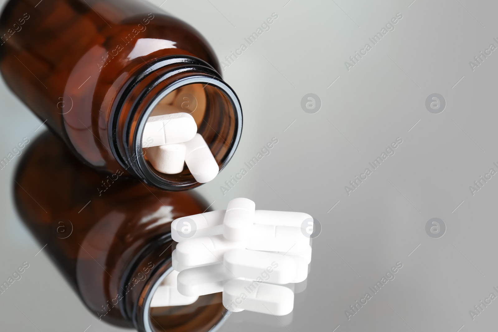 Photo of Bottle with pills on reflective surface