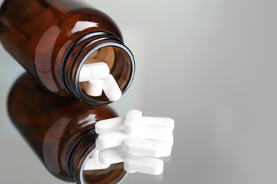 Photo of Bottle with pills on reflective surface