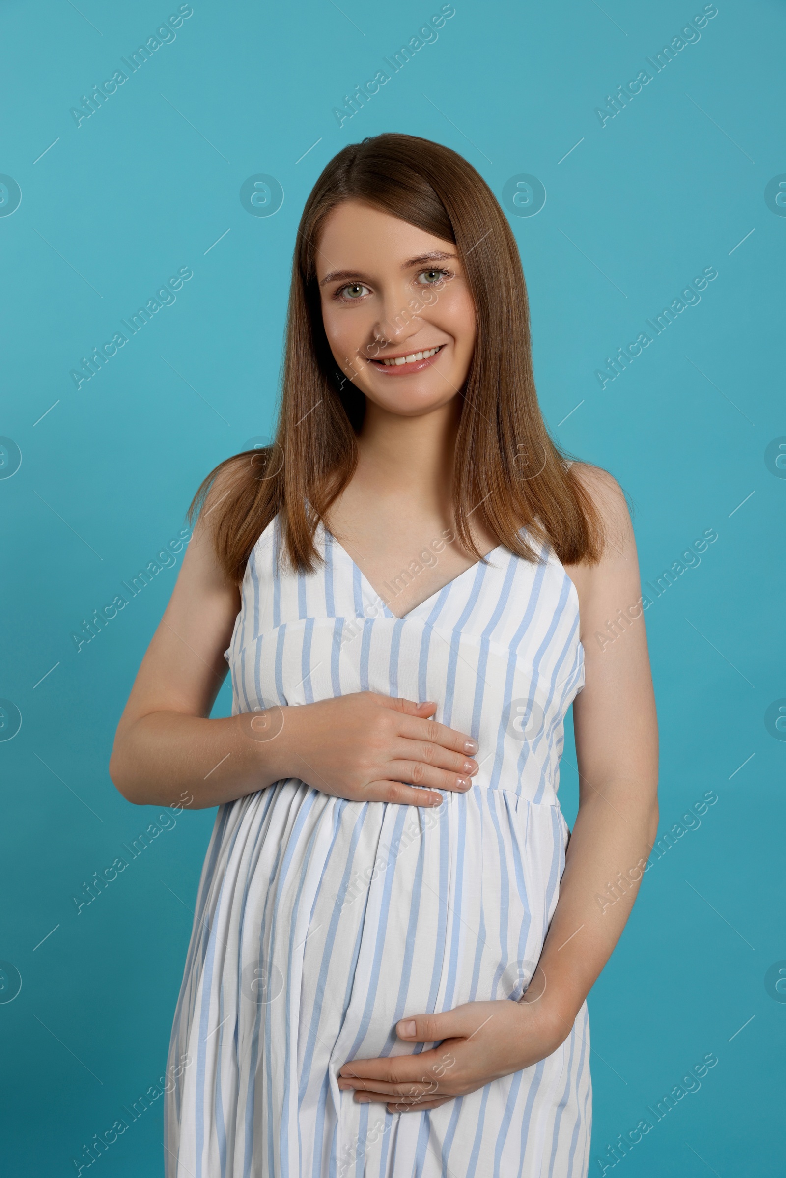 Photo of Happy young pregnant woman on light blue background