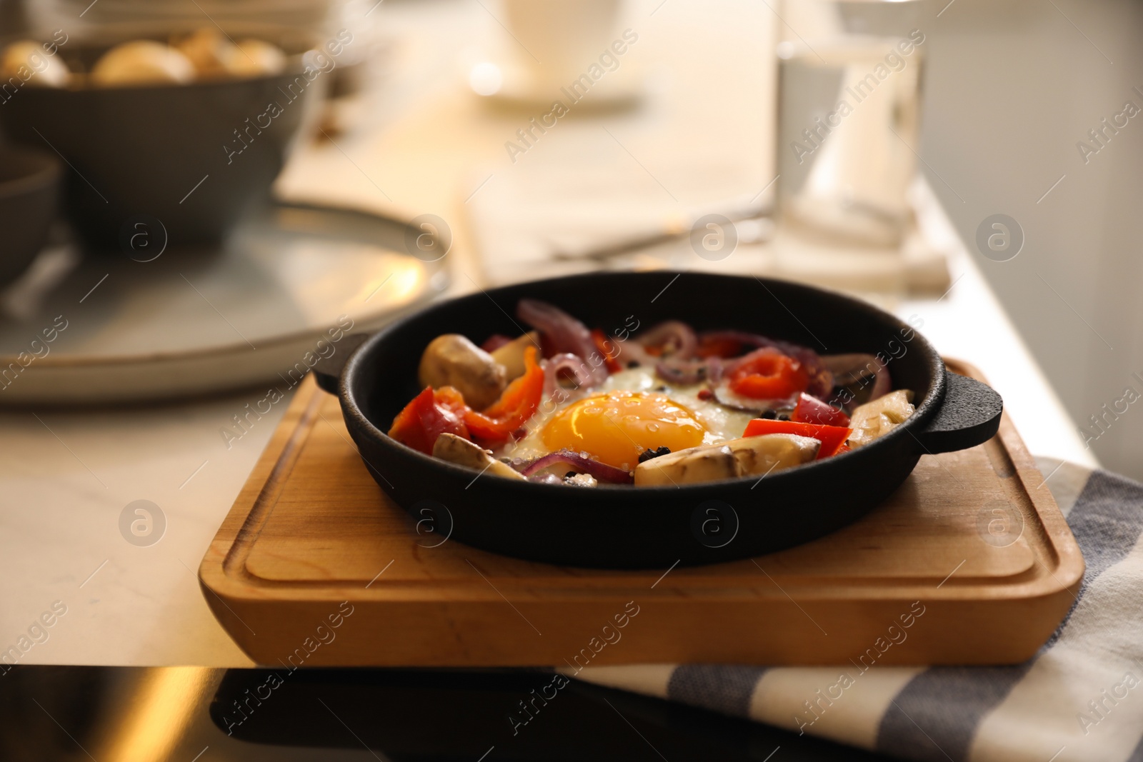 Photo of Tasty egg with vegetables in frying pan on wooden board