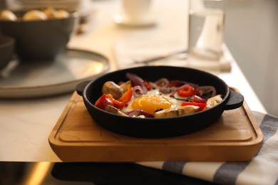 Photo of Tasty egg with vegetables in frying pan on wooden board
