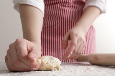 Photo of Woman kneading fresh dough at light grey table, closeup