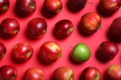 Photo of Green apple among red ones on color background, flat lay