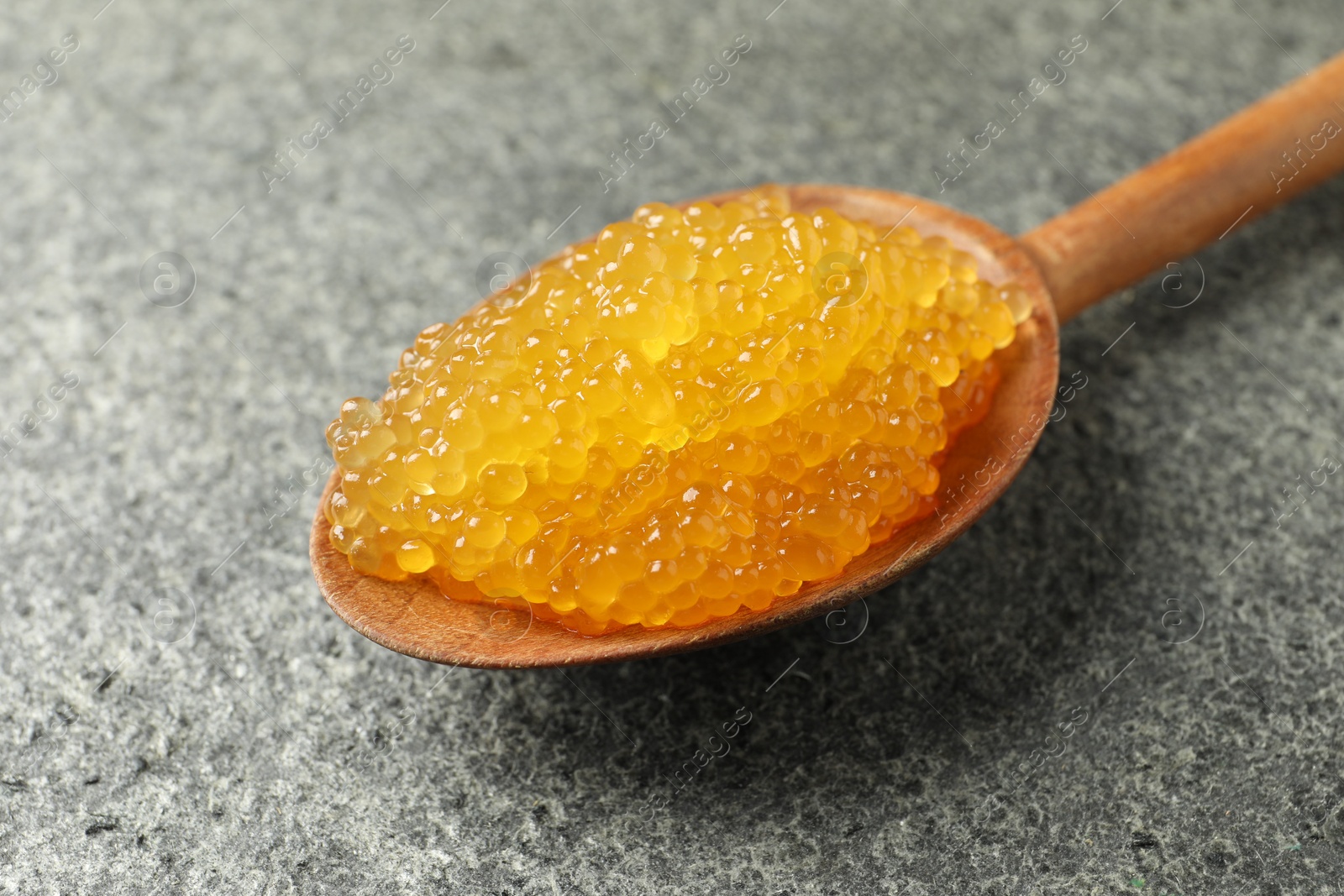 Photo of Fresh pike caviar in spoon on grey table, closeup