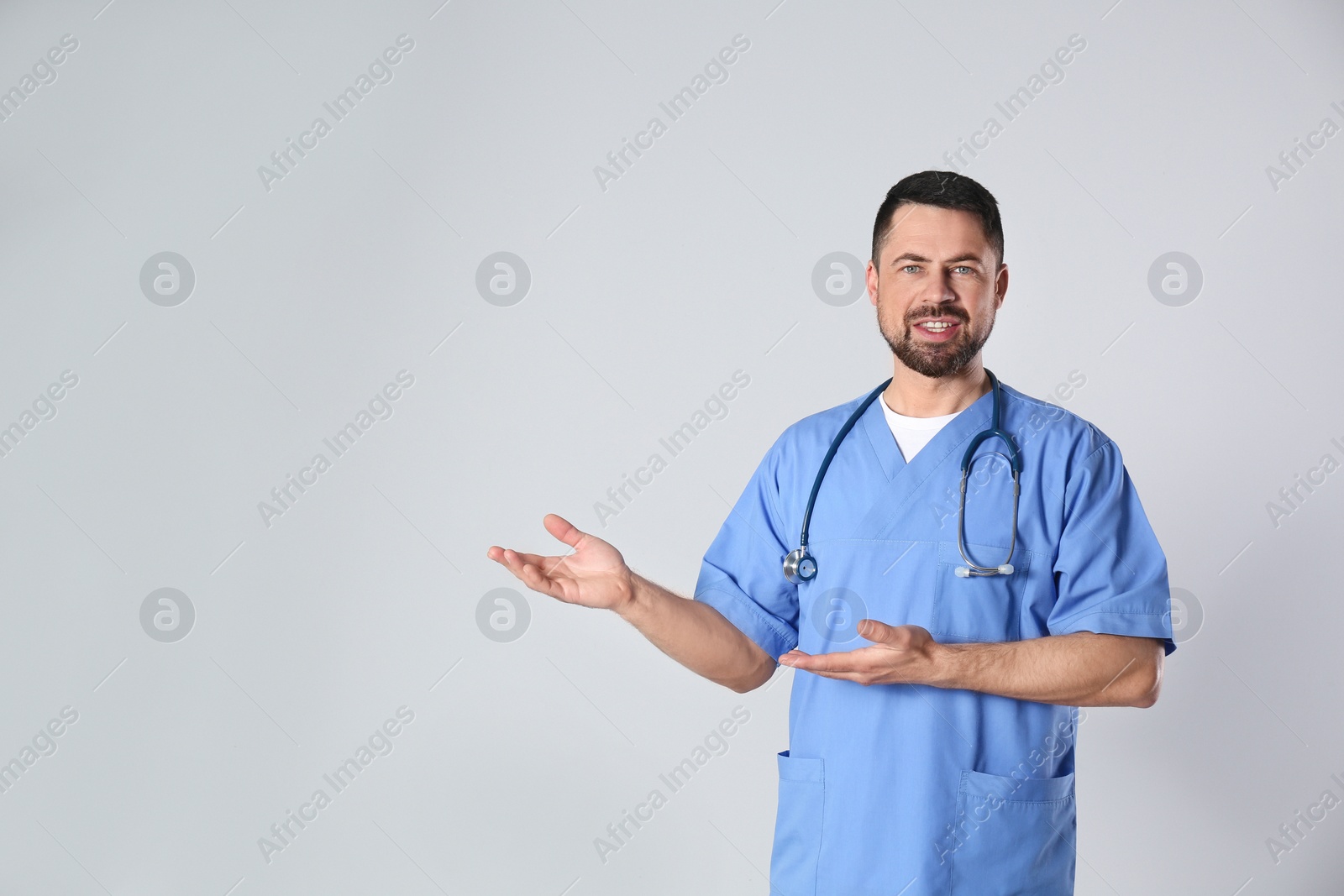 Photo of Portrait of mature doctor against light background