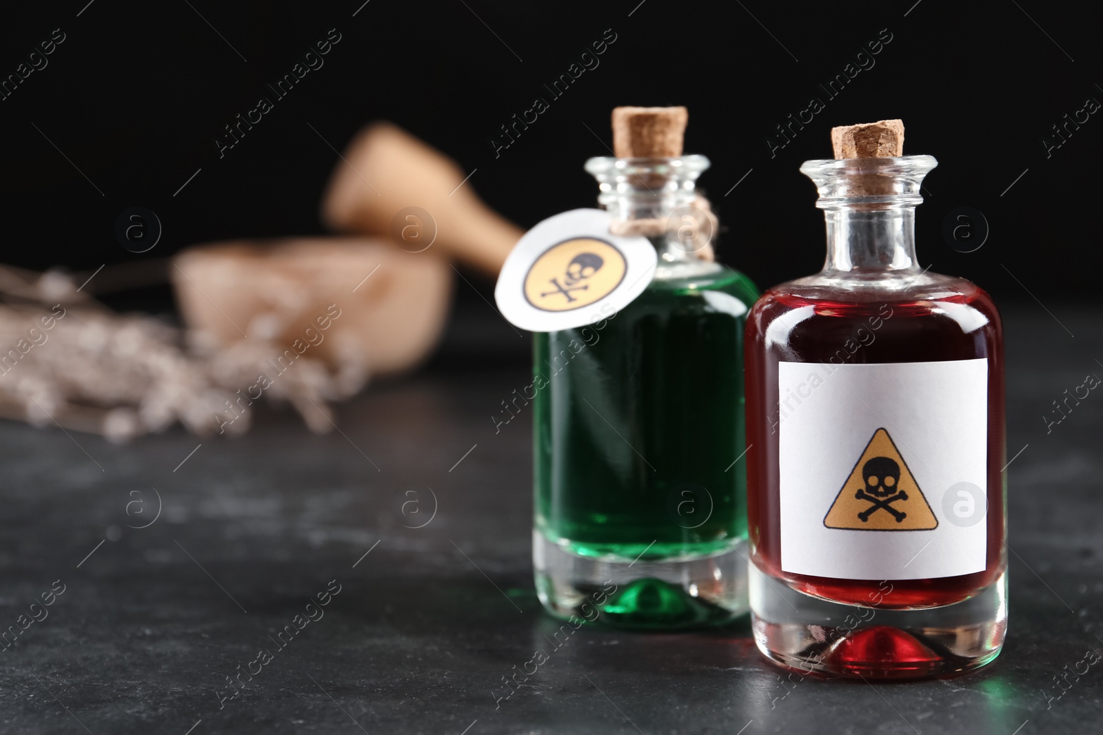 Photo of Glass bottles of poisons with warning signs on black table. Space for text