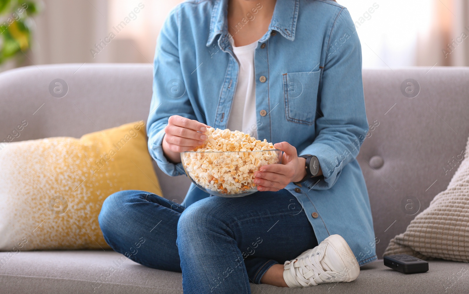 Photo of Young woman watching movie with popcorn in living room, closeup