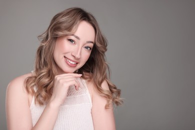 Photo of Portrait of smiling woman with curly hair on grey background. Space for text