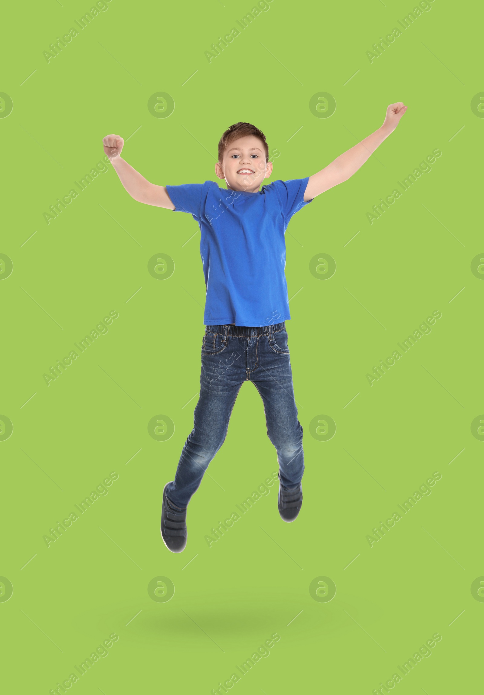 Image of Happy boy jumping on light green background, full length portrait