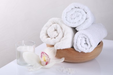 Spa composition with towels, orchid flower, candle and sea salt on white table