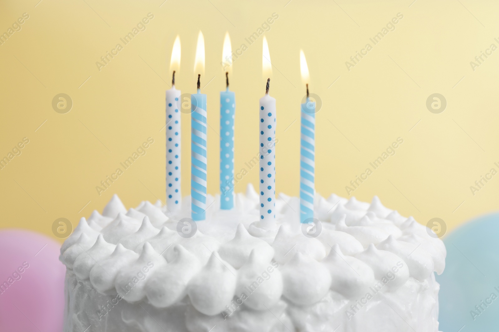 Photo of Delicious cake with cream and burning candles on yellow background, closeup