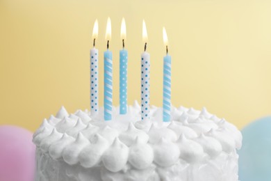Photo of Delicious cake with cream and burning candles on yellow background, closeup