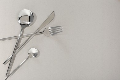 Stylish cutlery set on light grey background, flat lay. Space for text