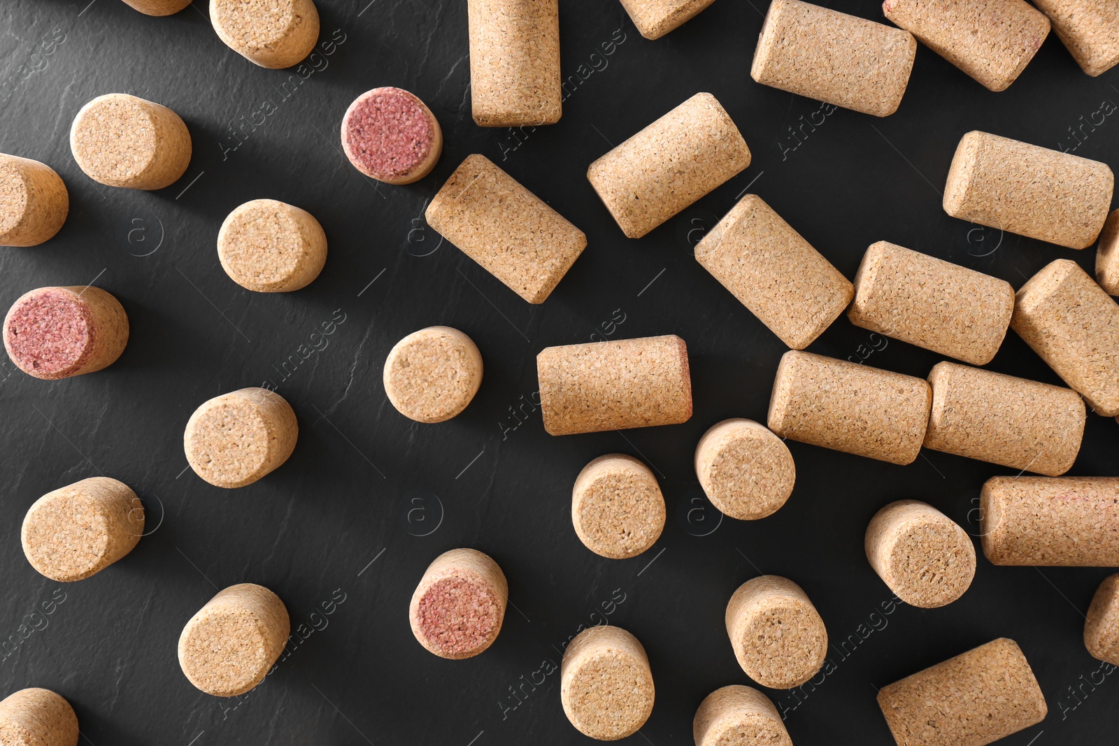 Photo of Wine bottle corks on black table, flat lay