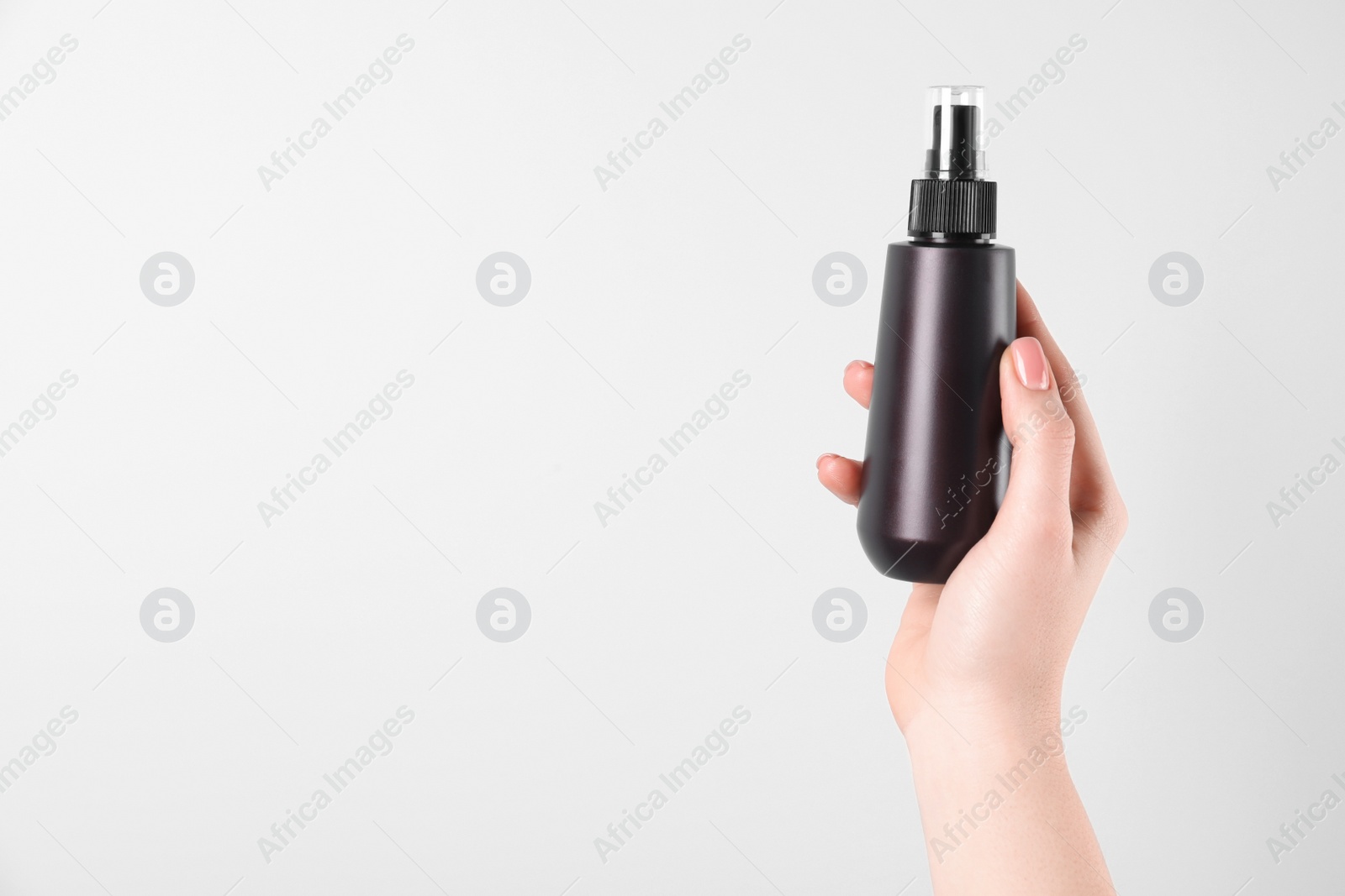 Photo of Woman holding spray bottle with hair thermal protection on white background, closeup. Space for text