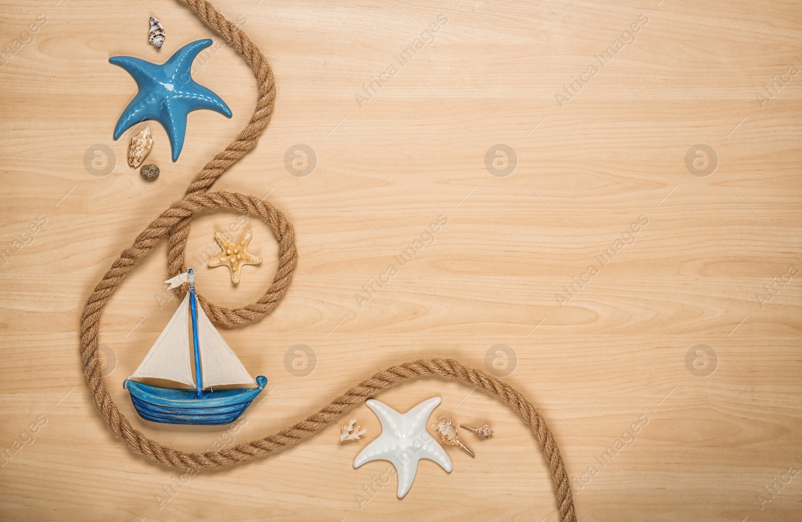 Photo of Flat lay composition with small boat and rope on wooden background. Beach objects