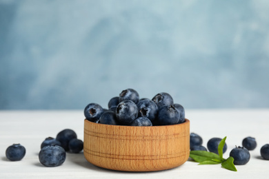 Photo of Fresh ripe blueberries in bowl on white wooden table