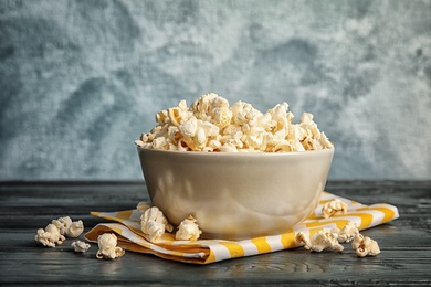 Photo of Bowl of tasty popcorn on wooden table