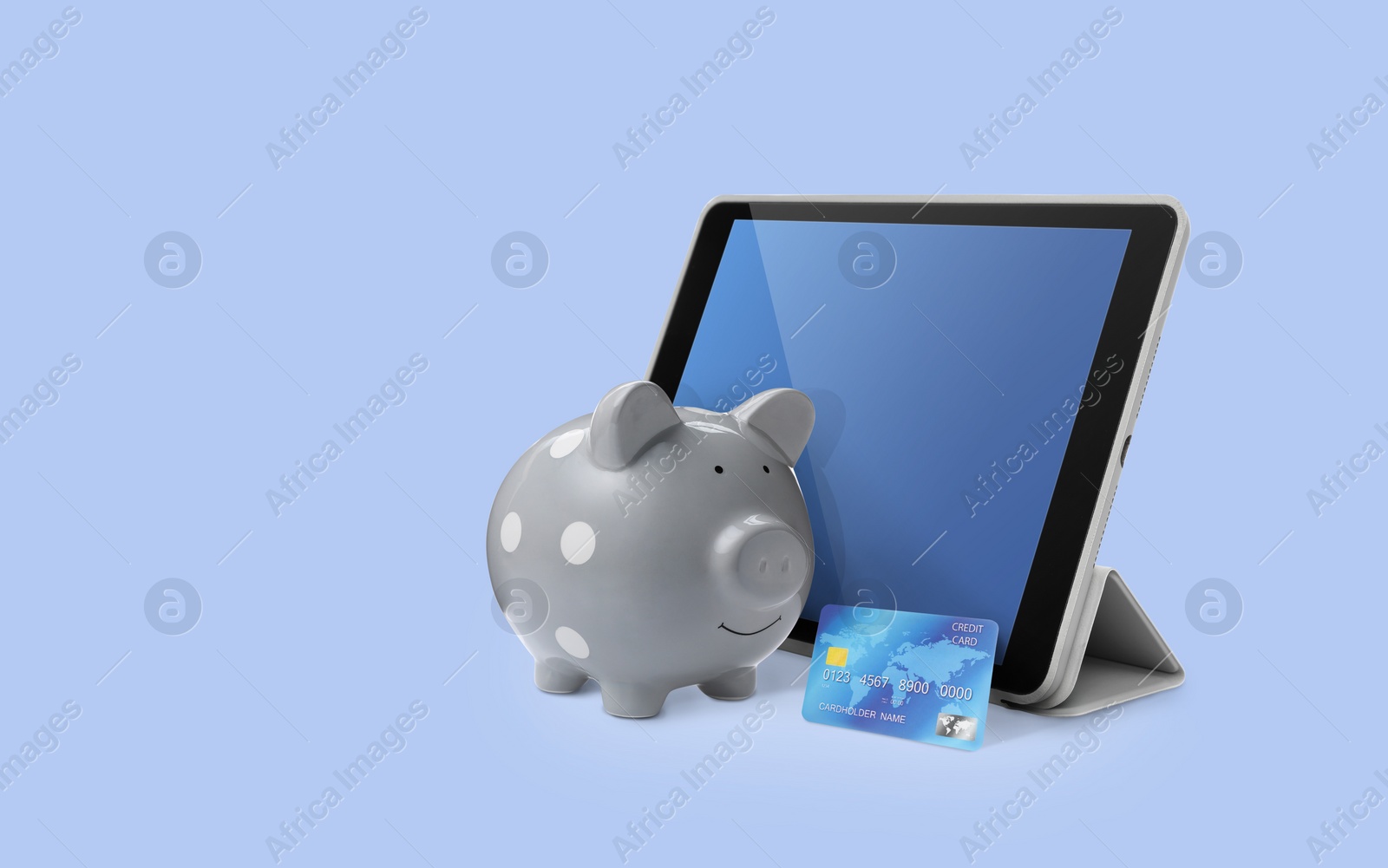 Image of Piggy bank with credit card and tablet on color background. Online banking