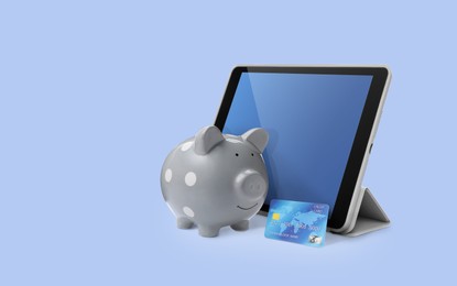 Piggy bank with credit card and tablet on color background. Online banking