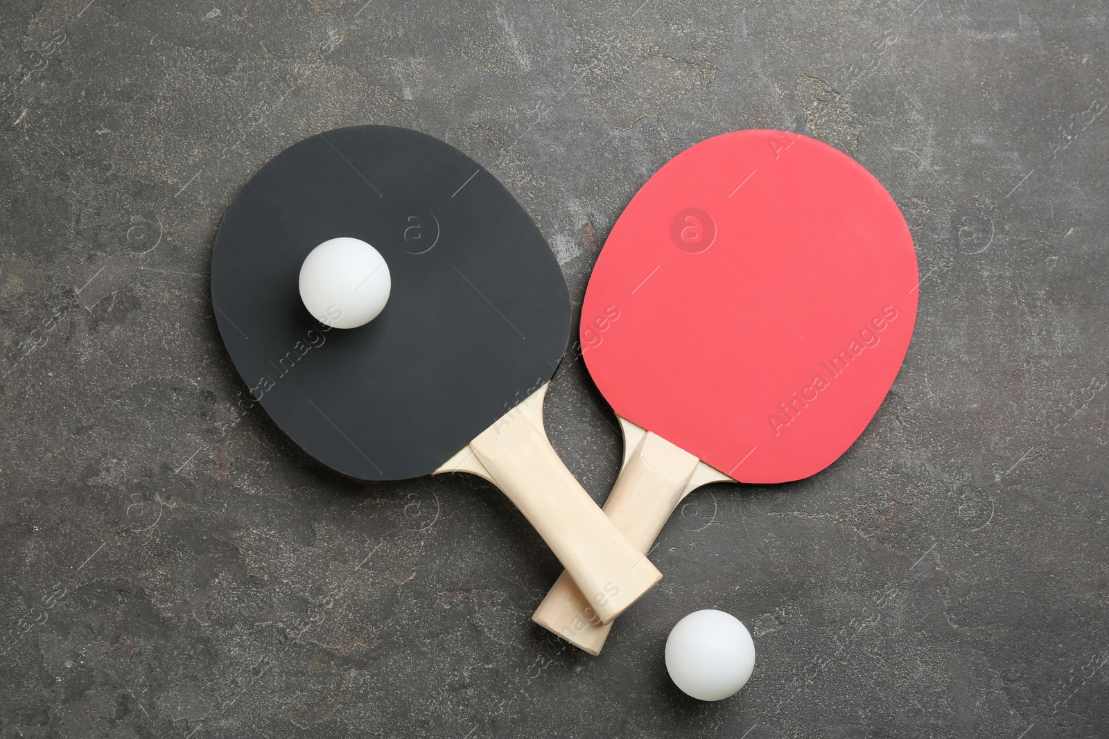 Photo of Ping pong rackets and balls on grey table, flat lay