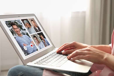 Woman visiting dating site via laptop indoors, closeup